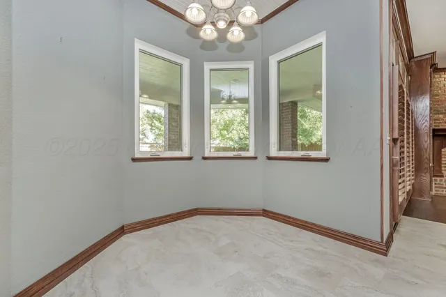 an empty room with windows and chandelier