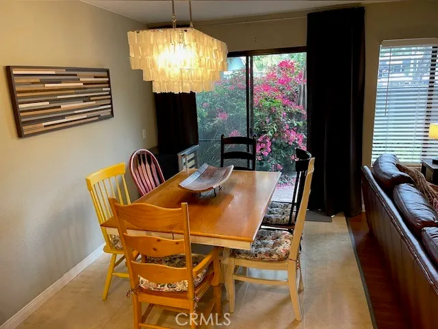 a view of a dining room with furniture a chandelier and large windows
