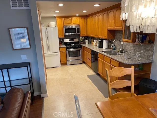 a kitchen with stainless steel appliances granite countertop a refrigerator a stove and a sink with wooden floor