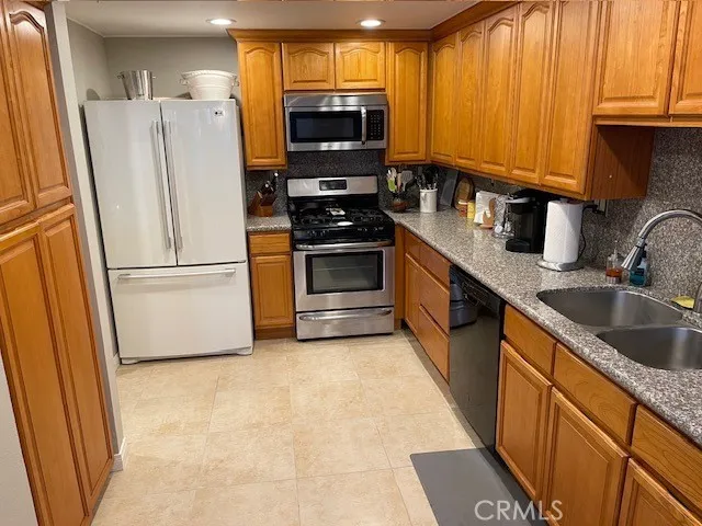 a kitchen with granite countertop a refrigerator and a sink