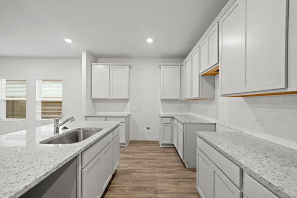 a kitchen with a sink dishwasher a stove and white cabinets with wooden floor