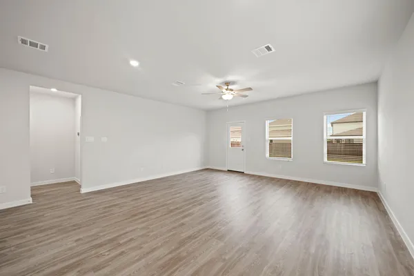 a view of an empty room with wooden floor and window