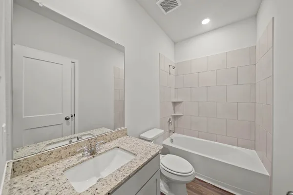 a bathroom with a granite countertop sink a toilet and shower