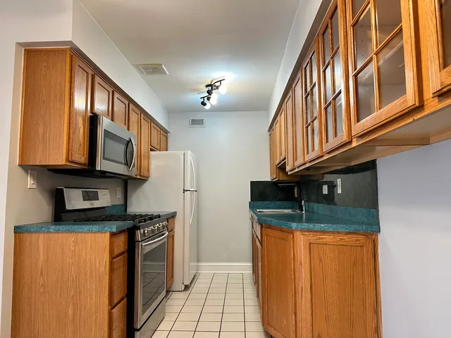 a kitchen with stainless steel appliances granite countertop a refrigerator and a stove top oven