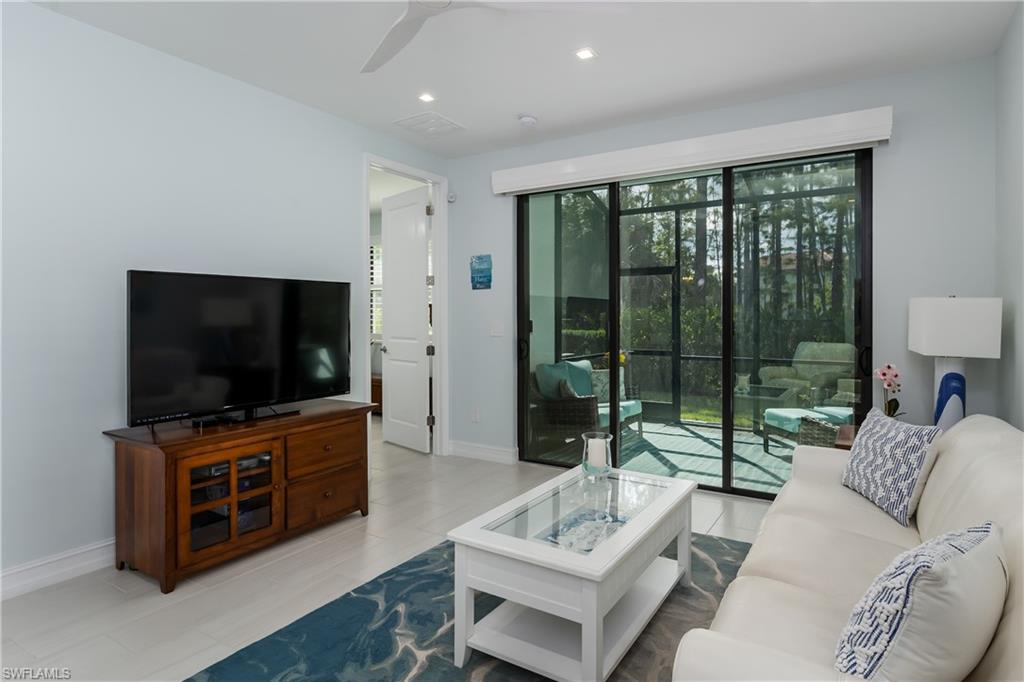 7336 Rockefeller Drive Naples, FL 34119 - Photo 7 of 50 a living room with furniture a flat screen tv and a floor to ceiling window