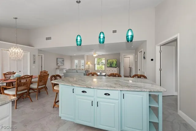 a dining hall with granite countertop a sink white cabinets and chairs