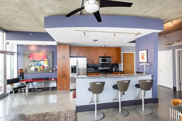 a kitchen with stainless steel appliances kitchen island granite countertop a refrigerator a stove a microwave oven a dining table and chairs with wooden floor