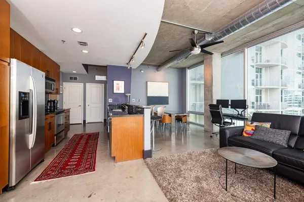 a kitchen with stainless steel appliances granite countertop a stove a refrigerator a couch and a dining table with wooden floor