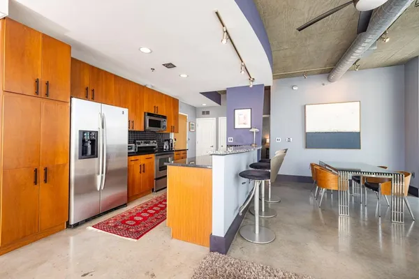 a kitchen with stainless steel appliances kitchen island granite countertop a refrigerator a stove a oven with white cabinets and couches