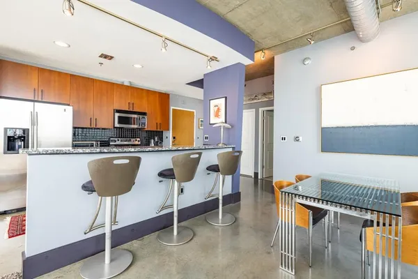 a kitchen with stainless steel appliances kitchen island granite countertop a table chairs in it and a window