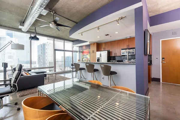 a open kitchen with stainless steel appliances granite countertop a refrigerator a sink dishwasher a dining table and chairs with wooden floor