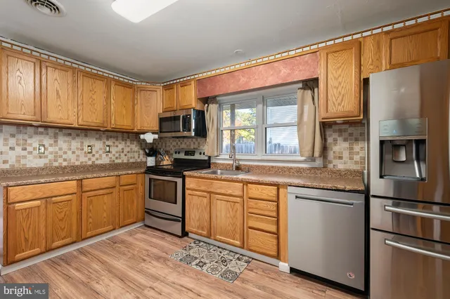 a kitchen with stainless steel appliances granite countertop a refrigerator a stove top oven a sink and dishwasher