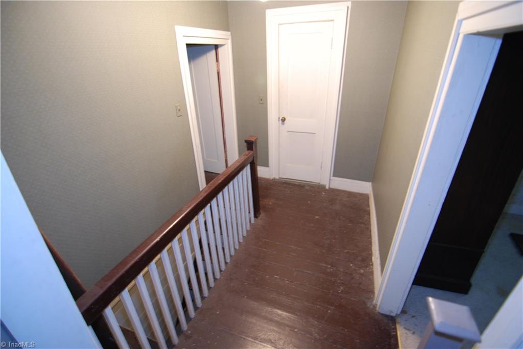 1036 Covington House Road Walnut Cove, NC 27052 - Photo 25 of 29 Upstairs hallway located at the rear of the home. Left door leads to large bathroom. Small door leads to the outside rear upper porch. Doorway to the right leads to a small spare room.