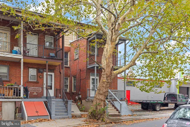 a front view of a building with large trees