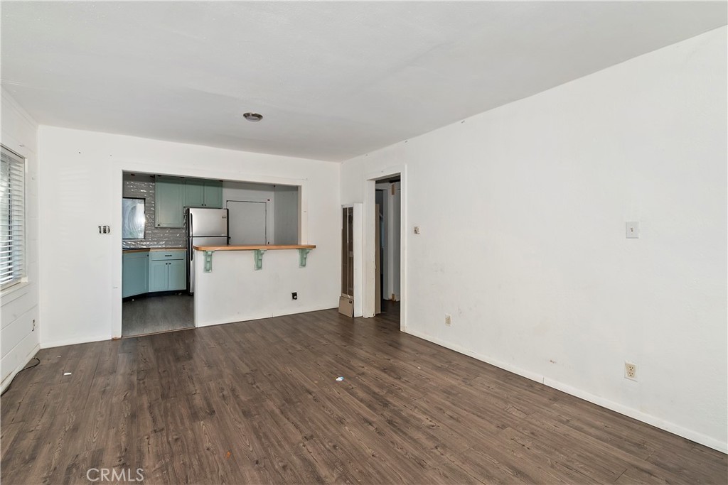 26331 Alpine Lane Twin Peaks, CA 92391 - Photo 20 of 41 a view of empty room with wooden floor and kitchen view