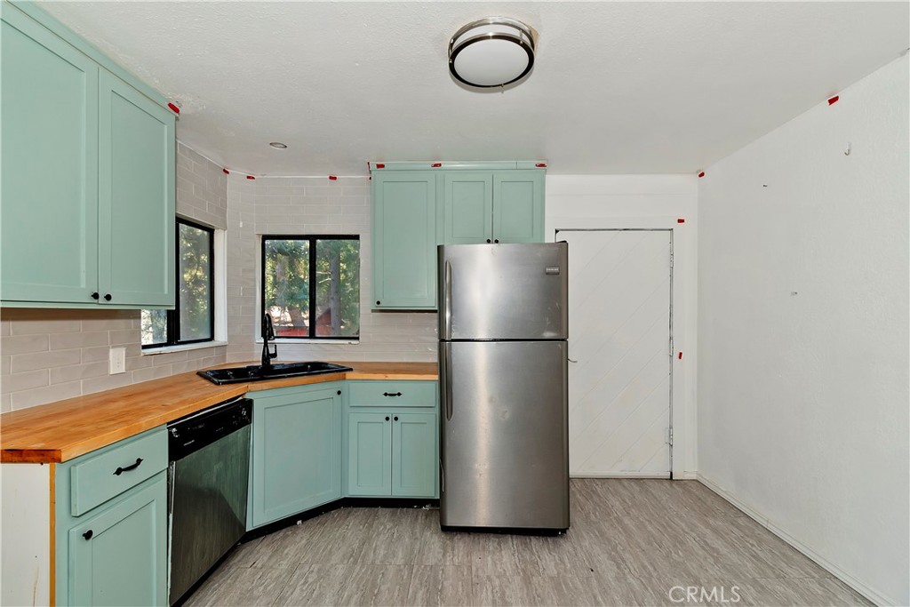 26331 Alpine Lane Twin Peaks, CA 92391 - Photo 4 of 41 a kitchen with a refrigerator a sink dishwasher and white cabinets with wooden floor