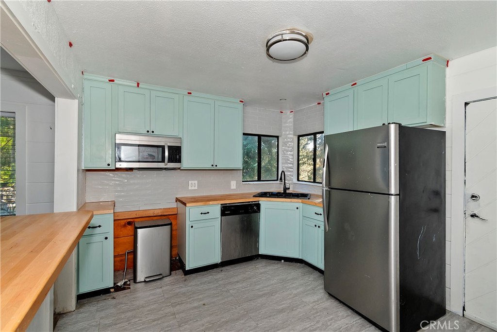26331 Alpine Lane Twin Peaks, CA 92391 - Photo 6 of 41 a kitchen with stainless steel appliances a refrigerator a sink a stove a microwave and island