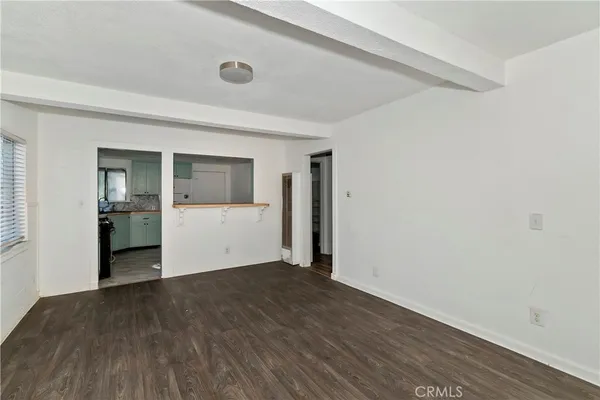 a view of a big room with wooden floor and kitchen