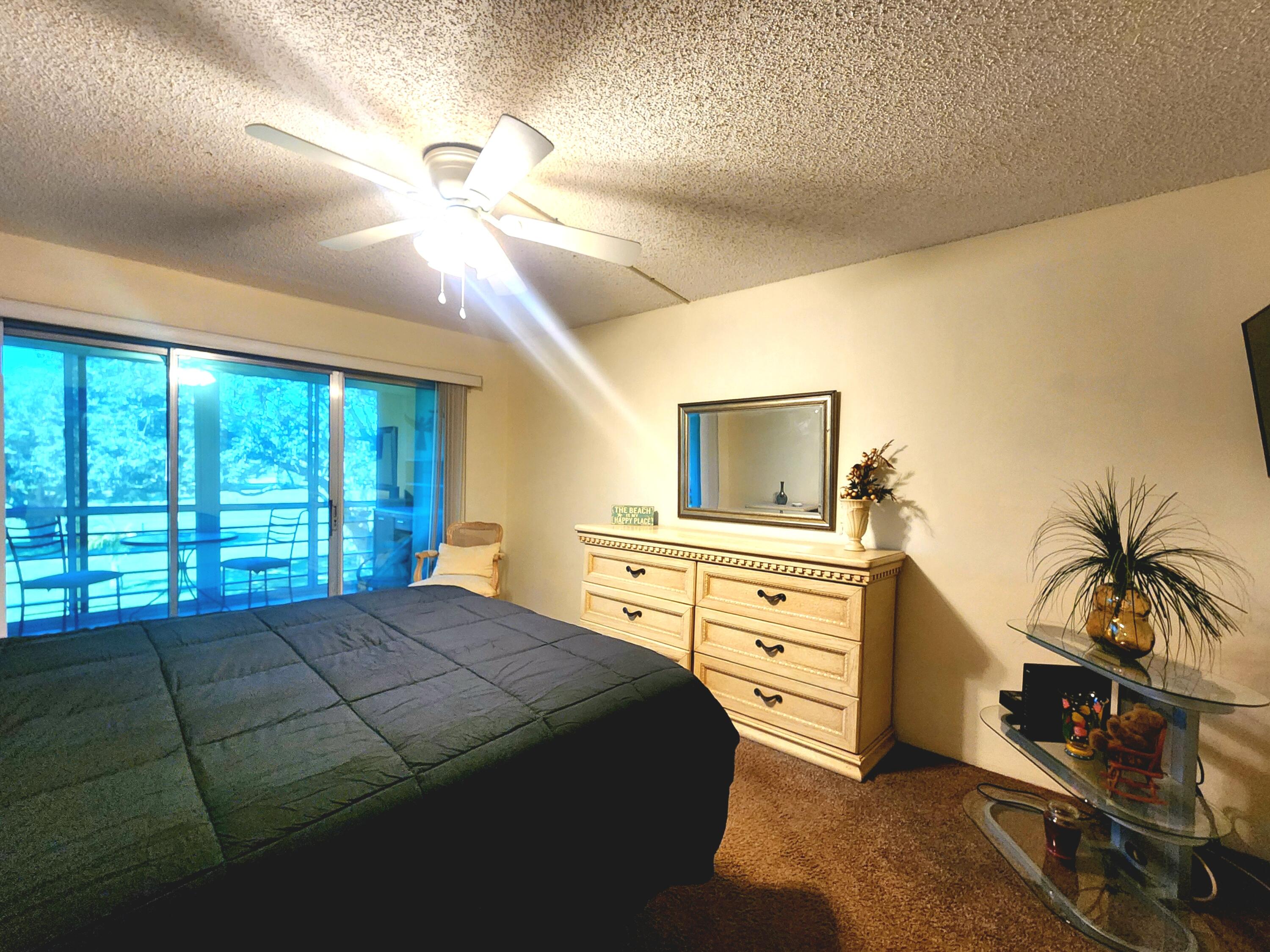 3959 Via Poinciana, Unit 208 Lake Worth, FL 33467 - Photo 18 of 32 a bedroom with a bed and ceiling fan