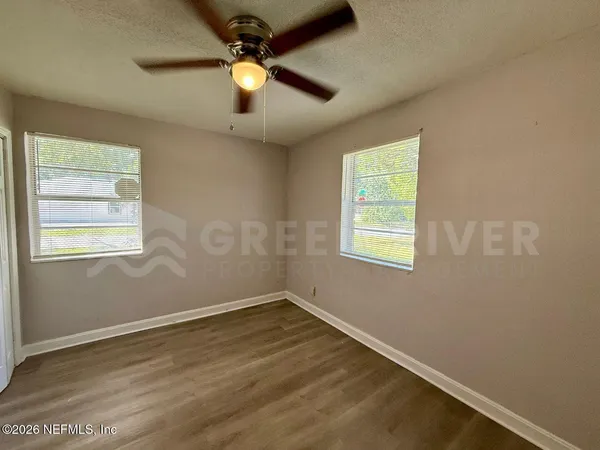 an empty room with wooden floor closet and ceiling fan