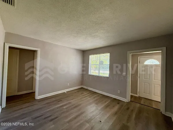 an empty room with wooden floor and windows