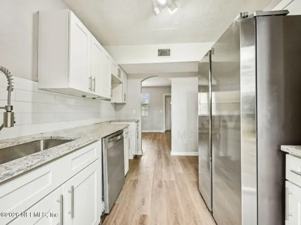 a kitchen with granite countertop white cabinets and white appliances