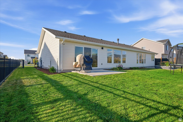 1422 West 3410th Street South Logan, UT 84321 - Photo 27 of 33 Spacious backyard featuring a substantial concrete patio, extensive green lawn, and a black metal fence