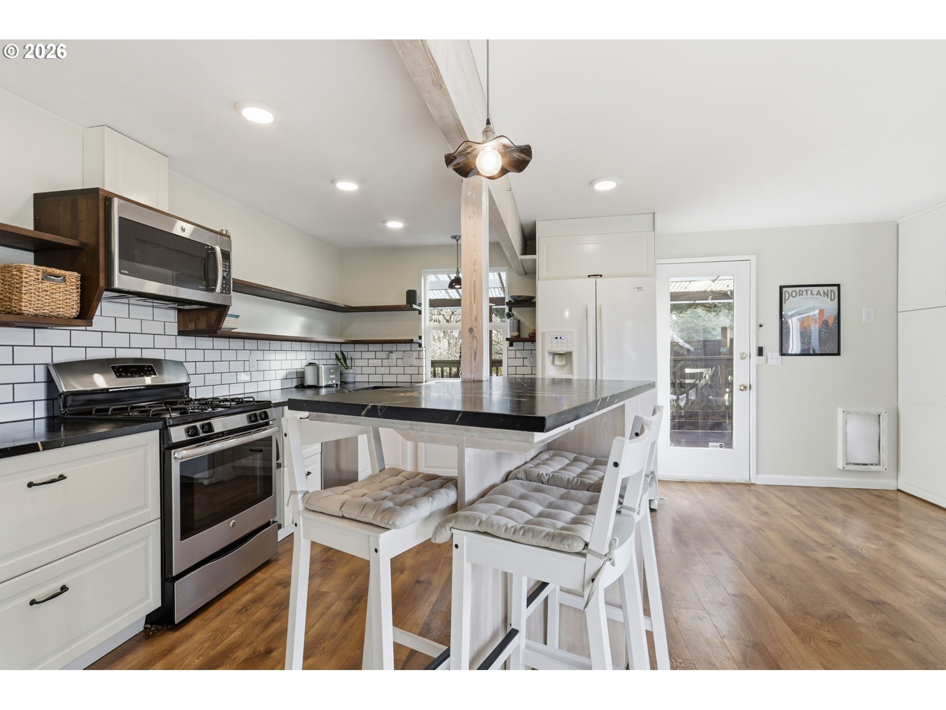 19350 Southwest Murphy Street Beaverton, OR 97078 - Photo 6 of 45 a kitchen with stainless steel appliances kitchen island granite countertop a stove a sink a microwave a refrigerator and white cabinets with wooden floor