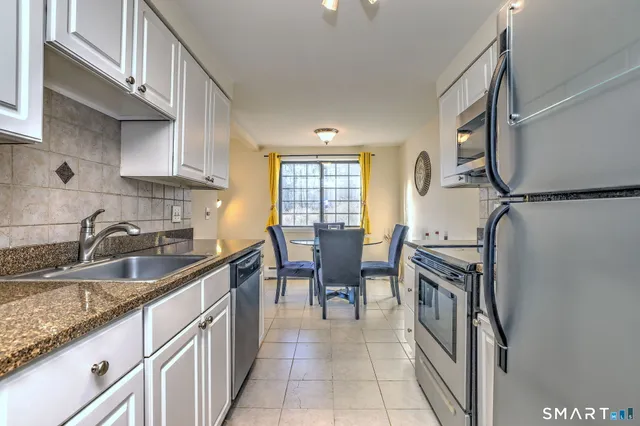 a kitchen with granite countertop a sink a counter top space and stainless steel appliances