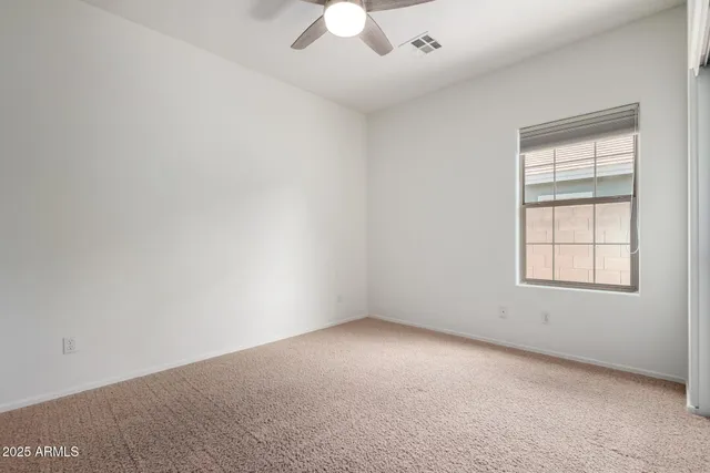 an empty room with a window and a fan