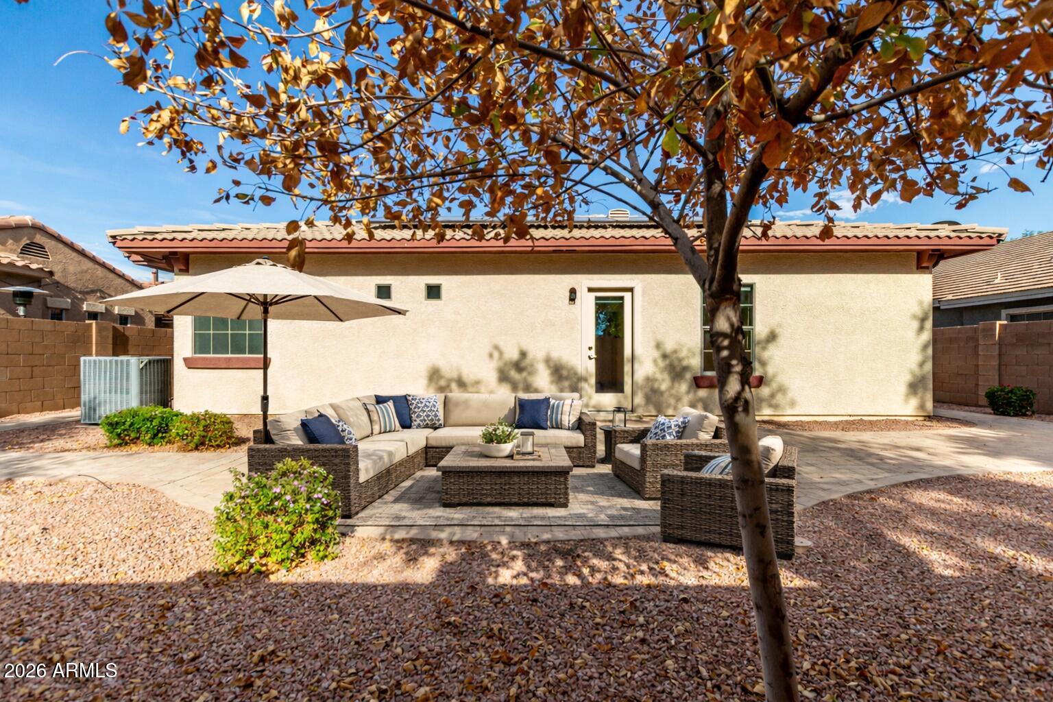 2602 South Nielson Street Gilbert, AZ 85295 - Photo 33 of 39 a view of a patio with couches table and chairs under an umbrella with a large tree