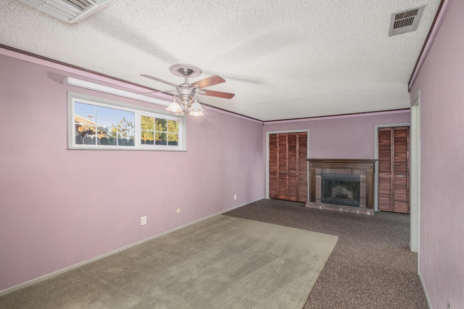 915 Fordham Avenue Clovis, CA 93611 - Photo 14 of 23 an empty room with windows a fireplace and a chandelier fan
