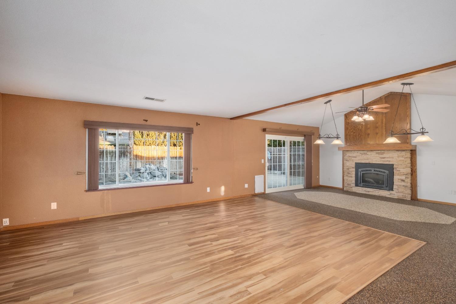 915 Fordham Avenue Clovis, CA 93611 - Photo 4 of 23 an empty room with windows fireplace and wooden floor