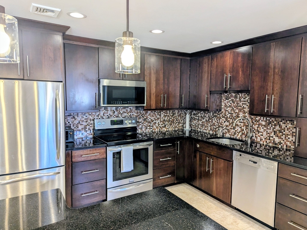 20 Central Street, Unit 405 Salem, MA 01970 - Photo 2 of 18 a kitchen with stainless steel appliances granite countertop wooden cabinets a stove top oven a sink and dishwasher