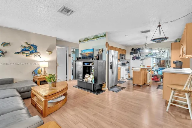 a kitchen with a refrigerator a stove a sink and a dining table with wooden floor