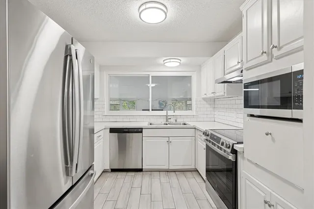 a kitchen with stainless steel appliances granite countertop a sink and stove top oven