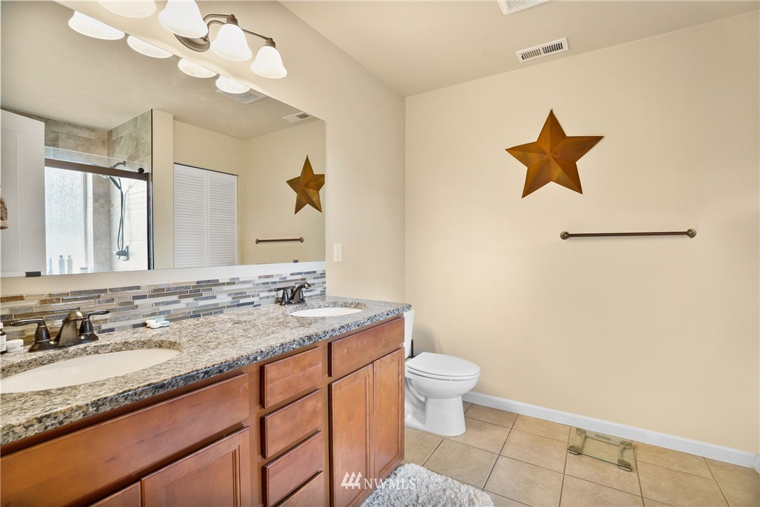 9327 179th Way Southwest Rochester, WA 98579 - Photo 12 of 20 a bathroom with a granite countertop sink a toilet and a mirror