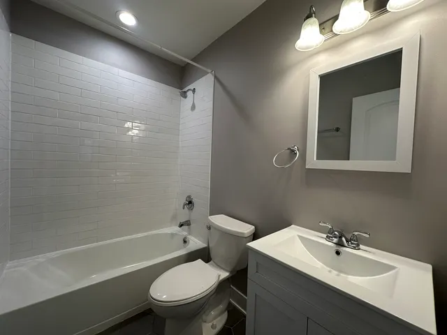 a bathroom with a toilet sink vanity and mirror