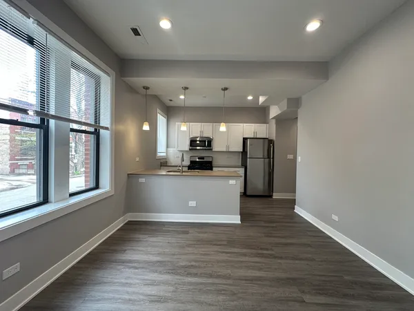 a view of kitchen with stainless steel appliances refrigerator oven large window and wooden floor