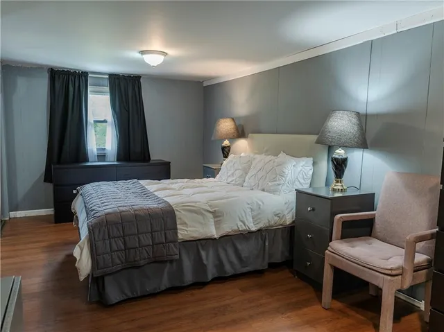 a bedroom with a bed a lamp and wooden floor