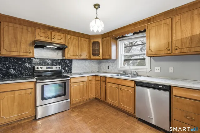 a kitchen with granite countertop wooden cabinets stainless steel appliances and a sink