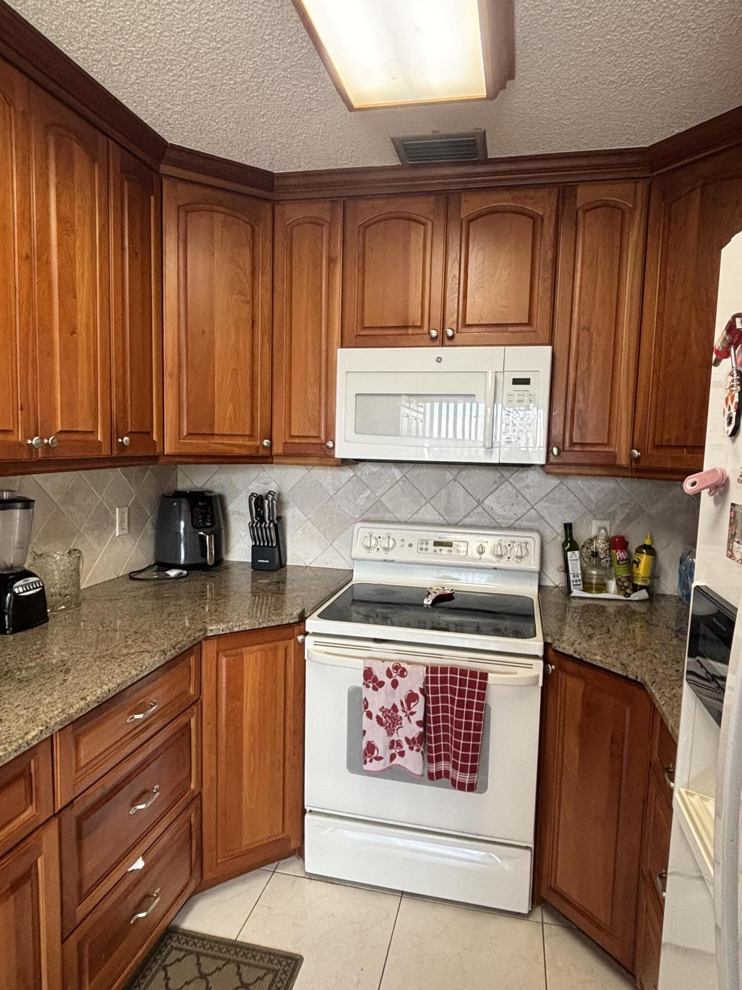 8833 Bella Vista Drive, Unit 8833 Boca Raton, FL 33433 - Photo 11 of 47 a kitchen with stainless steel appliances granite countertop a stove a sink dishwasher and cabinets with wooden floor