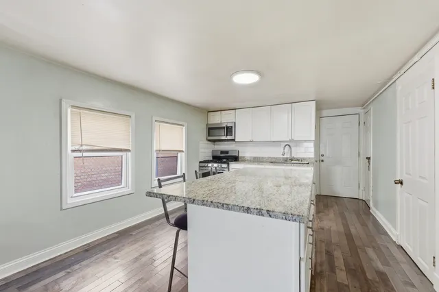 a large kitchen with kitchen island a stove a sink wooden floor and cabinets