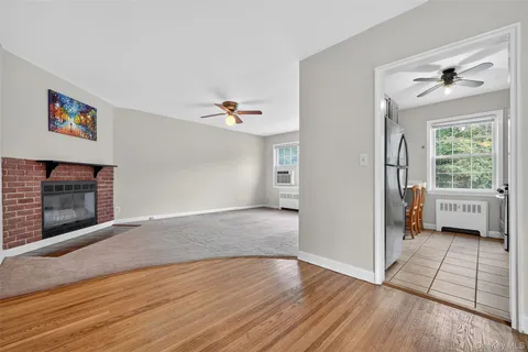 a view of an empty room with window and kitchen view