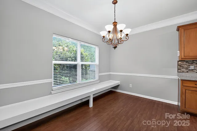 a dining room with wooden floor and a chandelier