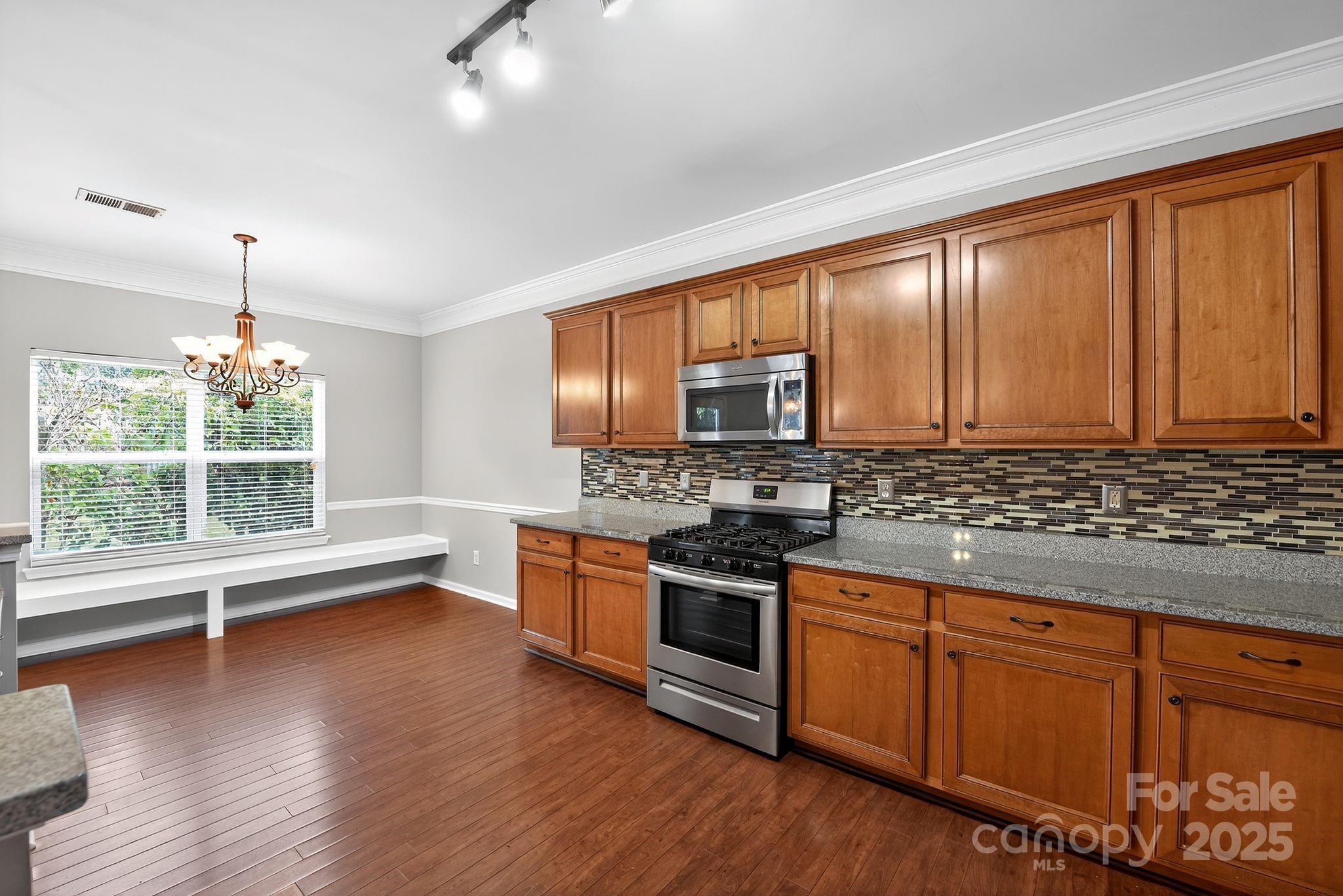3114 Less Traveled Trail Indian Trail, NC 28079 - Photo 19 of 32 a kitchen with stainless steel appliances granite countertop wooden cabinets a stove a sink and dishwasher with wooden floor
