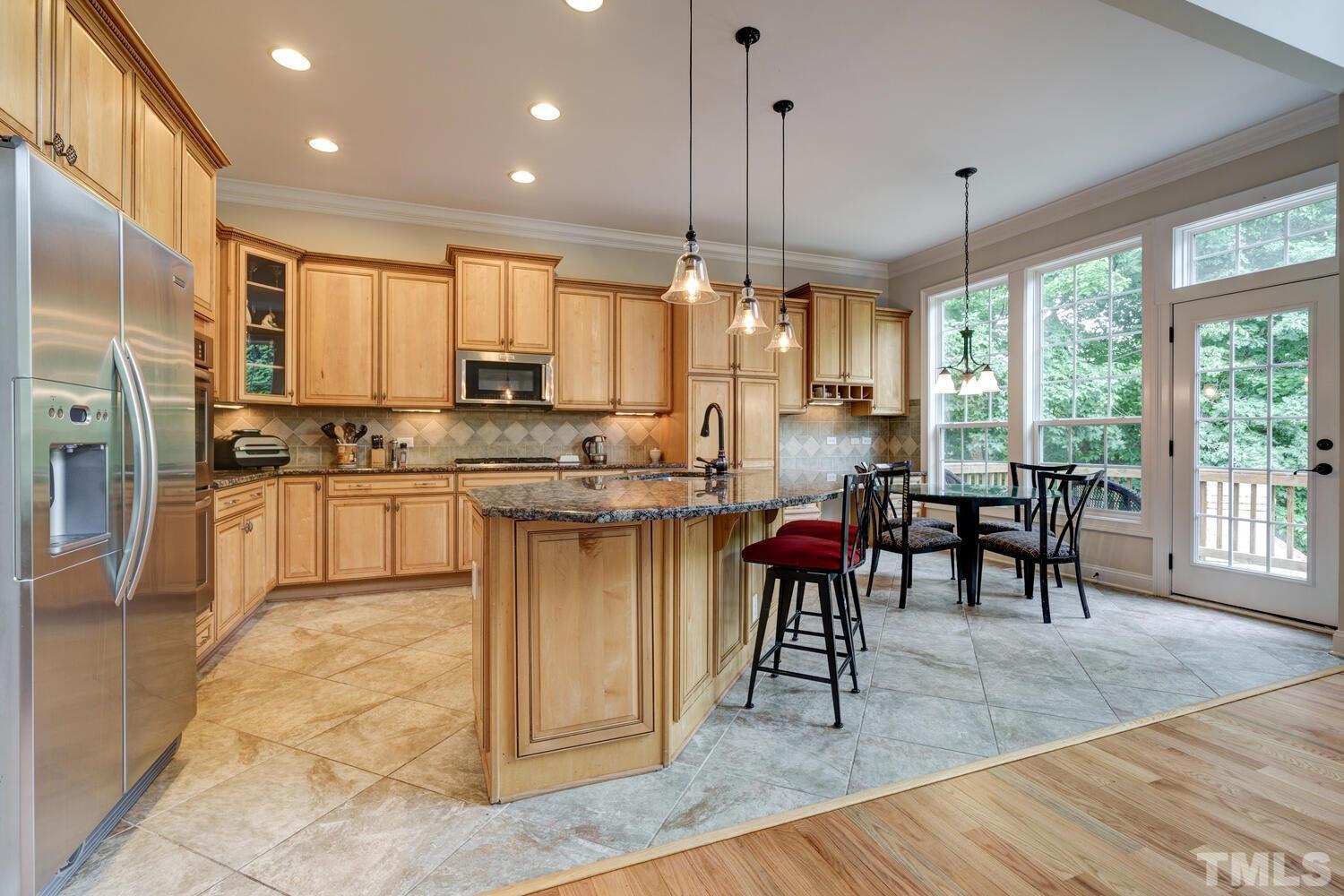 3907 Morvan Way Raleigh, NC 27612 - Photo 11 of 69 a kitchen with stainless steel appliances granite countertop wooden floor sink stove dining table and chairs