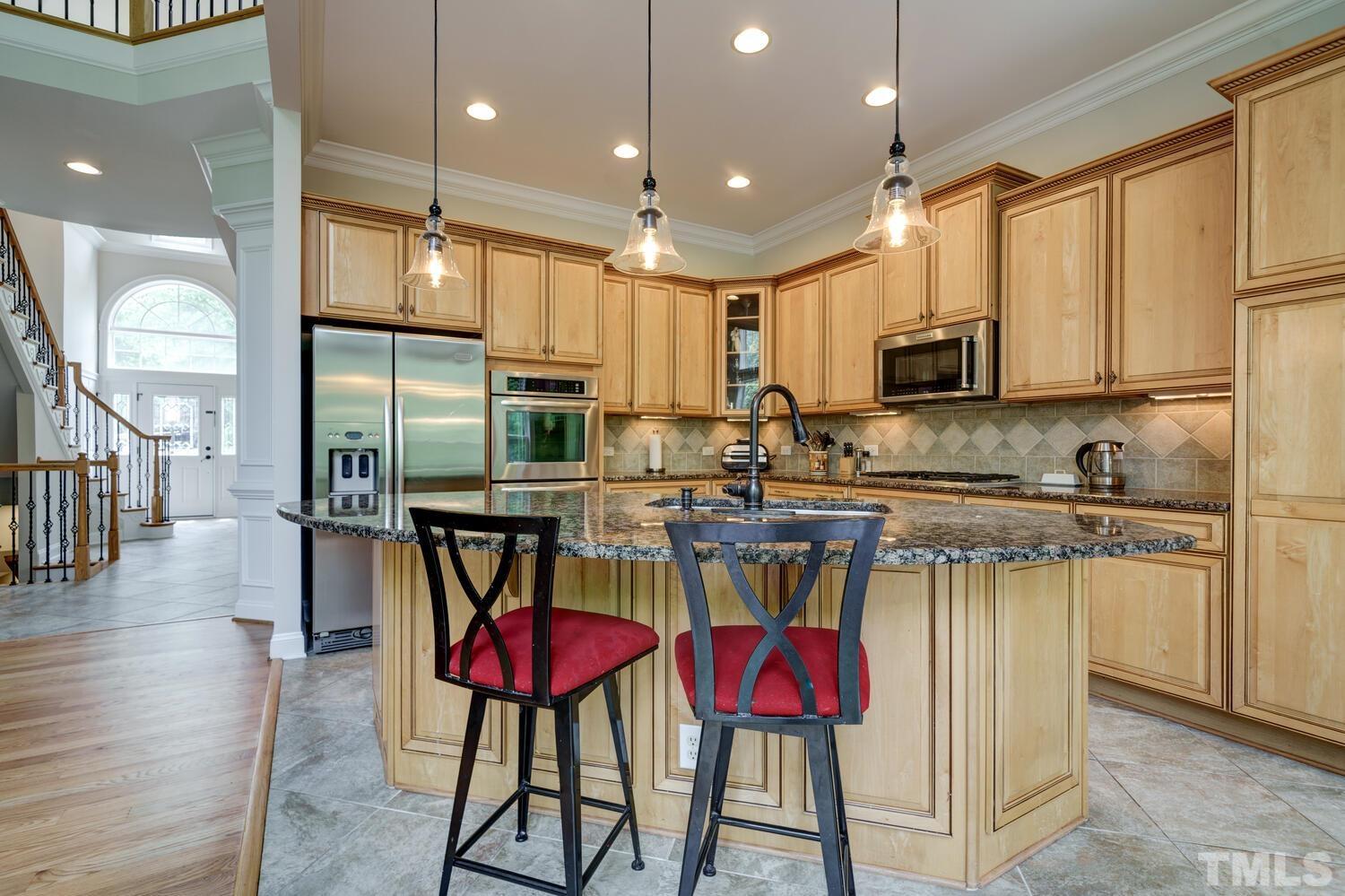 3907 Morvan Way Raleigh, NC 27612 - Photo 17 of 69 a kitchen with stainless steel appliances granite countertop a stove a sink a microwave a refrigerator and chairs