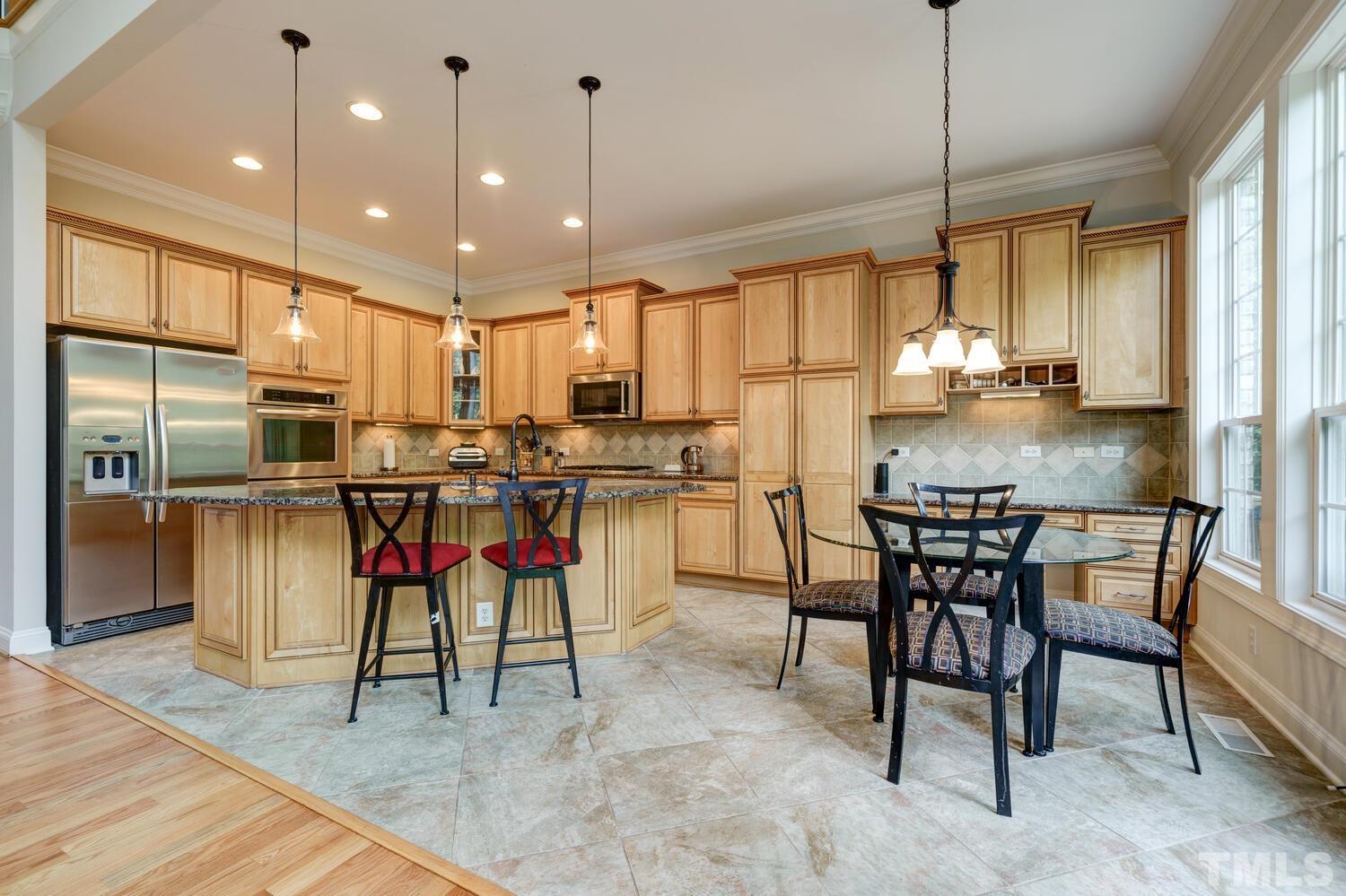 3907 Morvan Way Raleigh, NC 27612 - Photo 18 of 69 a kitchen with stainless steel appliances kitchen island granite countertop a table chairs sink and cabinets