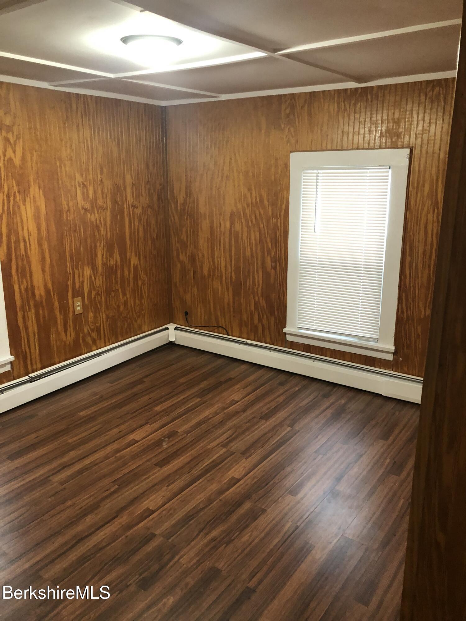 3-5 Pleasant Street Pittsfield, MA 01201 - Photo 37 of 40 an empty room with wooden floor and windows with curtains